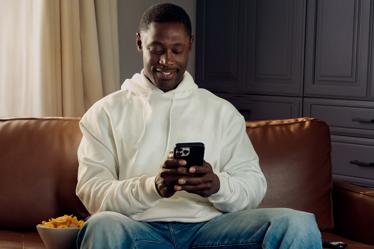 Man sitting on couch, playing on phone